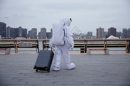 穿着宇航服的男性拖行李箱高清图片