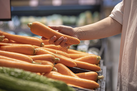 蔬菜货架手拿胡萝卜的手部特写背景