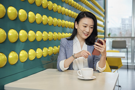 职场商务女性休闲喝咖啡看手机背景图片