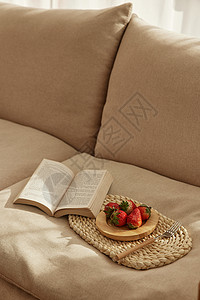 沙发上的草莓和书本背景图片