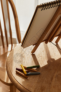 木桌特写圆桌上的绘画本和蜡笔特写背景