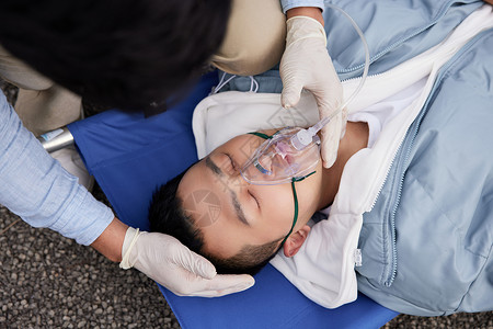 急救人员给病人带呼吸面罩特写图片