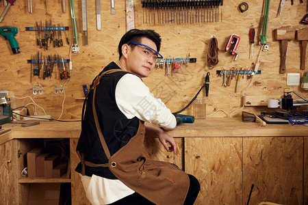 男性工匠在工作台打磨木具图片