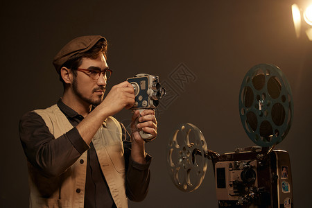 胶片摄影师文艺男青年摄影师拿着手持摄影机背景