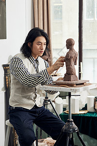 雕刻泥塑作品的男青年艺术家背景图片