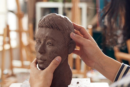 青年艺术家雕刻泥塑作品特写图片