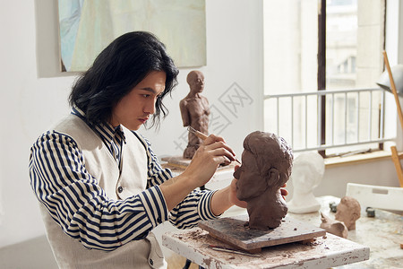 男雕刻艺术家雕刻泥塑作品背景图片