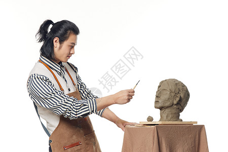 年轻男艺术家专注雕塑创作图片