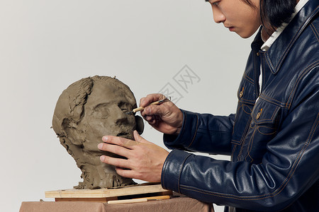 男艺术家认真雕刻泥塑作品特写图片