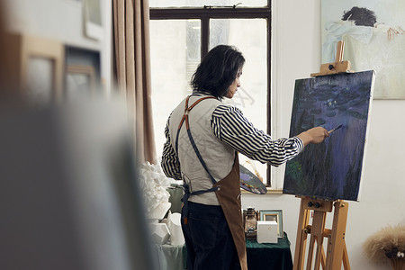 油画工作室专心油画创作的年轻男性背影背景