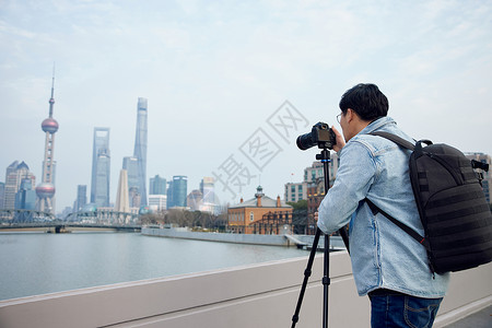 拍一张照片使用三脚架拍摄城市风光照的青年男性背景