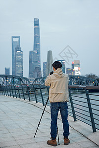 专业风控青年男性使用三脚架拍摄城市风光照背景