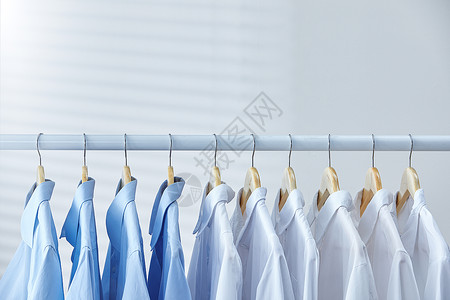 家居挂衣架白色衣架上晾晒着的蓝白衬衫背景