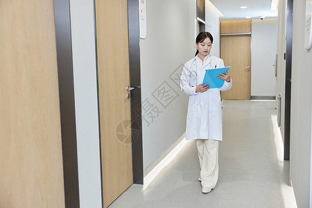 手拿病历本走在医院走廊的女医生图片