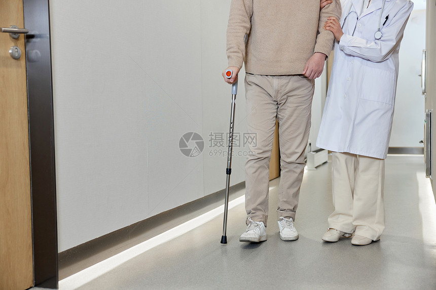 女医师搀扶腿伤病人走过走廊特写图片