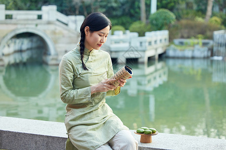 户外看书吃青团的青年美女背景图片