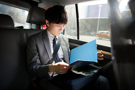 职场男青年坐在出租车里看文件高清图片