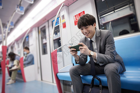 地铁商业地铁上玩手机的商务男性背景