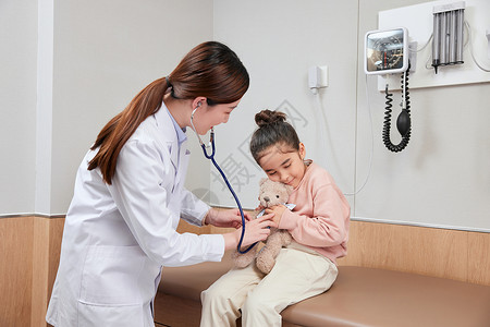 给小熊使用听诊器的小女孩和医生图片