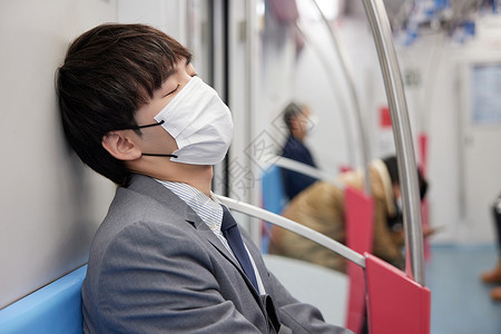迟到上班族戴着口罩的商务男青年疲惫坐地铁背景
