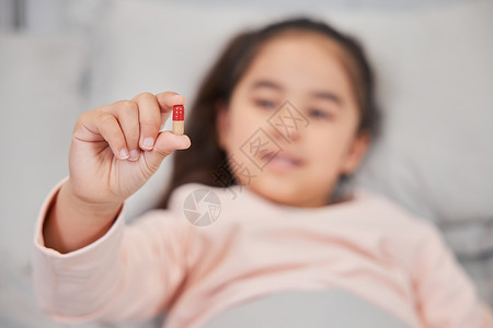 儿科急诊中心住院的小女孩手拿药丸特写背景