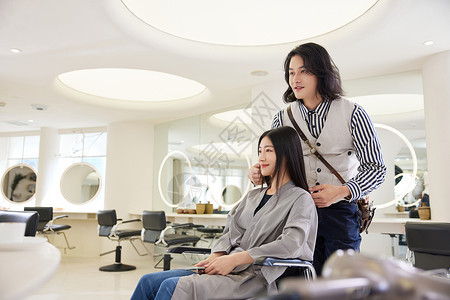 青年理发师跟女顾客沟通发型设计图片