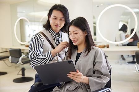 青年男理发师跟顾客沟通发型设计图片