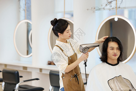 美女理发师使用吹风机给顾客吹头发图片