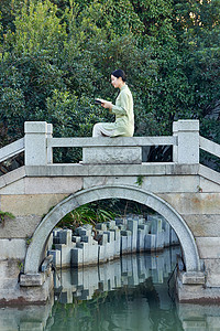坐在桥边看书的素雅美女背景图片