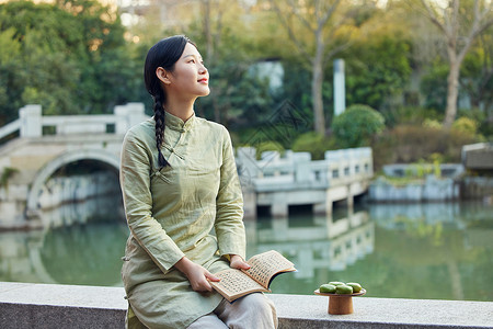 室外看书吃青团的青年女性背景图片