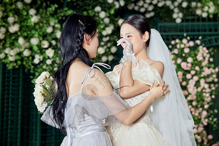 婚礼上与伴娘拥抱幸福落泪的新娘高清图片