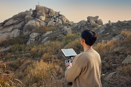 航拍摄影师登山使用无人机拍摄背影图片