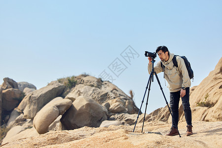 摄影师户外登山使用三脚架拍摄风景图片