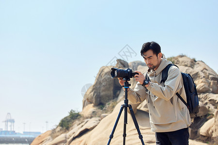 风光摄影师登山使用三脚架拍摄背景图片