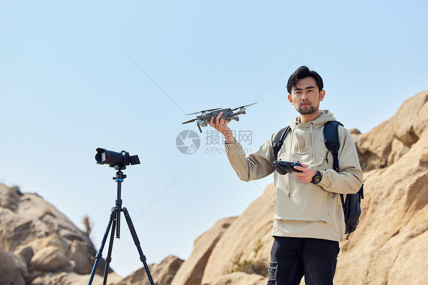 航拍摄影师山顶手拿无人机图片