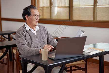 使用笔记本电脑看书的老年人背景图片