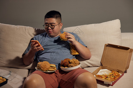 肥胖男士沙发玩手机吃夜宵高清图片