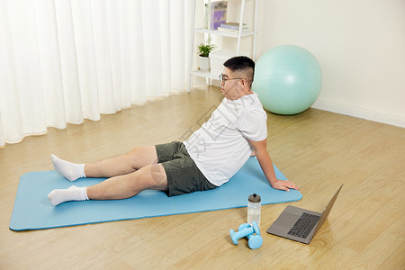 肥胖男青年瑜伽垫上擦汗休息高清图片
