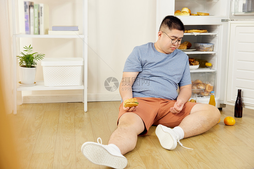 肥胖男士冰箱旁吃撑图片