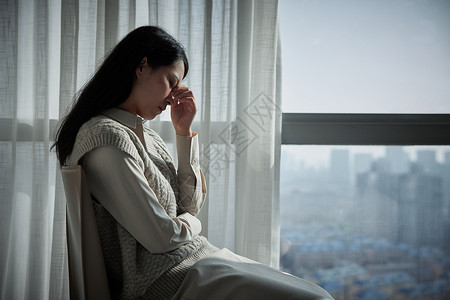 心情抑郁坐在窗边的抑郁青年女性背景