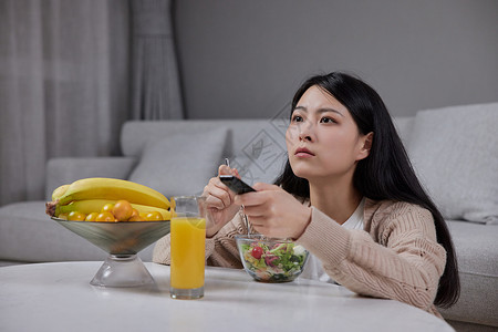 青年女性居家吃沙拉看电视背景图片