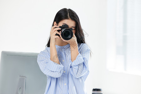 女摄影师影棚拍摄护肤品青年女摄影师手拿相机拍摄形象背景