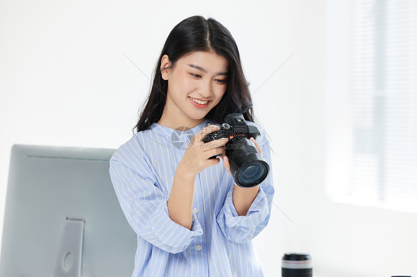 年轻女摄影师手拿相机拍摄图片