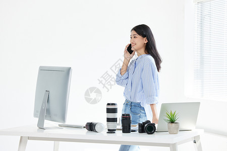 在工作室打电话的年轻女摄影师图片