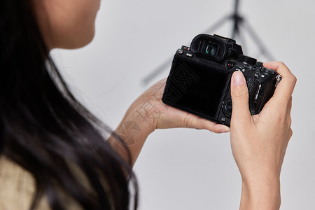 女摄影师影棚拍摄护肤品摄影师手拿单反相机特写背景