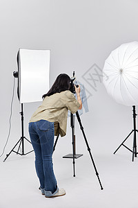 拍摄服装静物的女摄影师背影背景图片