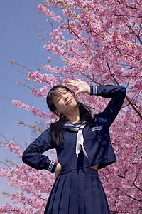 少女敬礼美女大学生逛游公园赏樱花背景