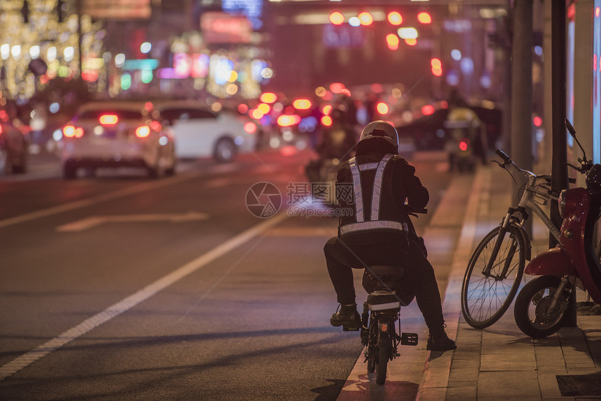 夜晚街道上忙碌的代驾小哥的背影图片