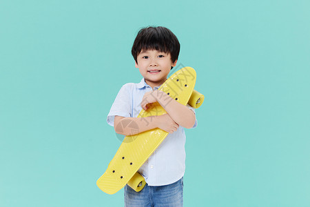 抱着滑板的小男孩背景图片