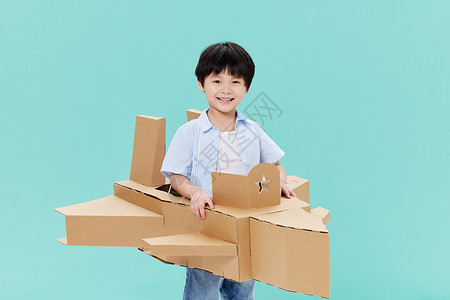 身穿纸板飞机模型玩耍的小男孩高清图片